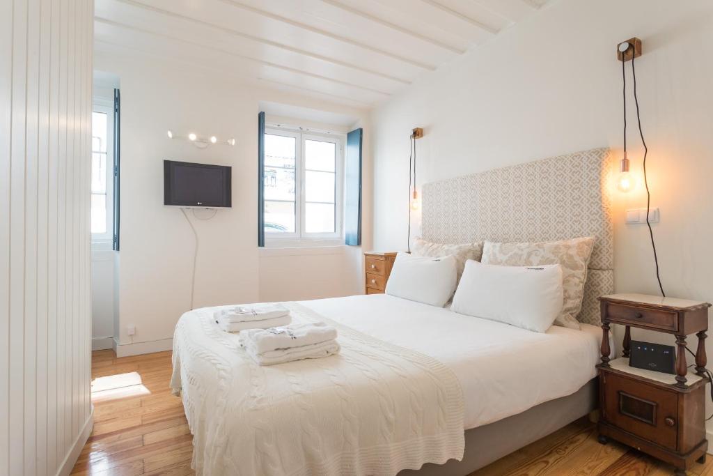 リスボンにあるFLH Bairro Alto Central Apartmentのベッドルーム1室(白いベッド1台、壁掛けテレビ付)