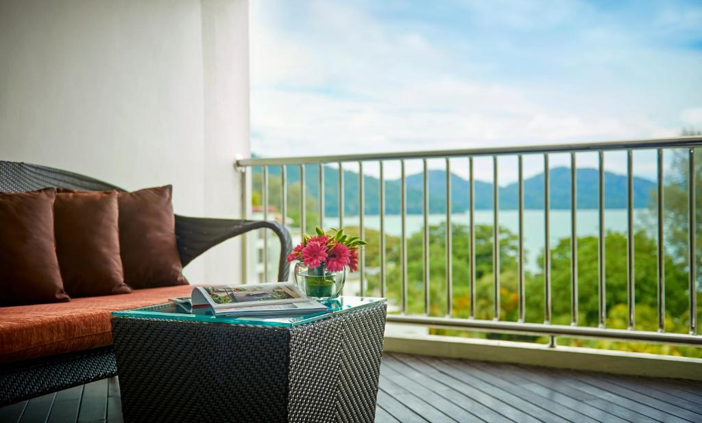 a table with a book on a balcony with a couch at PARKROYAL Penang Resort in Batu Ferringhi