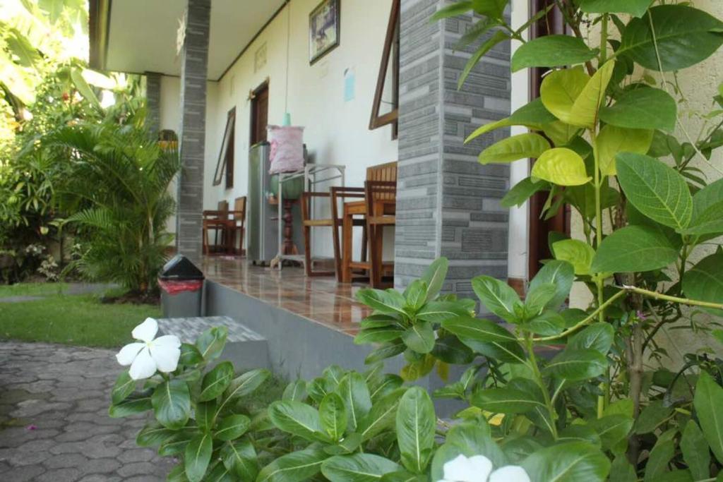 a porch of a house with some white flowers at Twins Homestay in Canggu
