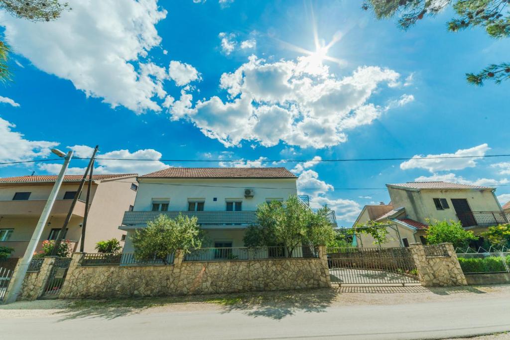 een huis met de zon in de lucht bij Apartments Brekalo in Pakoštane