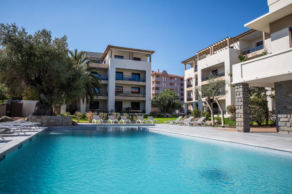 a swimming pool in a hotel with chairs and buildings at Residence Saletta Casale in LʼÎle-Rousse