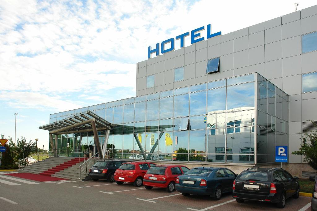 un gran edificio con coches estacionados en un estacionamiento en Hotel Zovko Zagreb en Sesvete