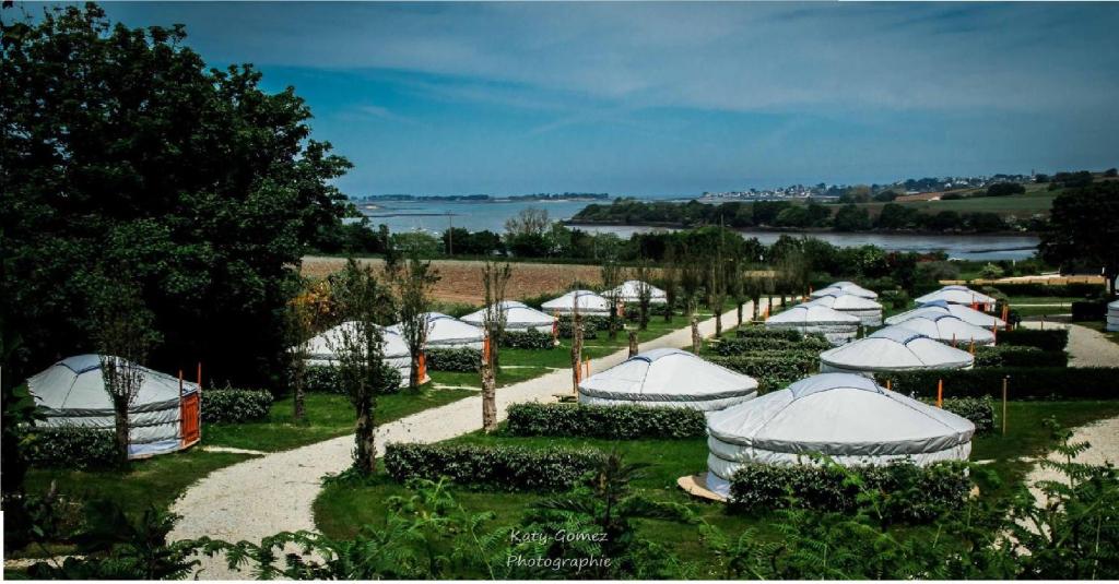 a row of white tents in a garden at Camping Kerlaudy Mer et Yourtes in Plouénan