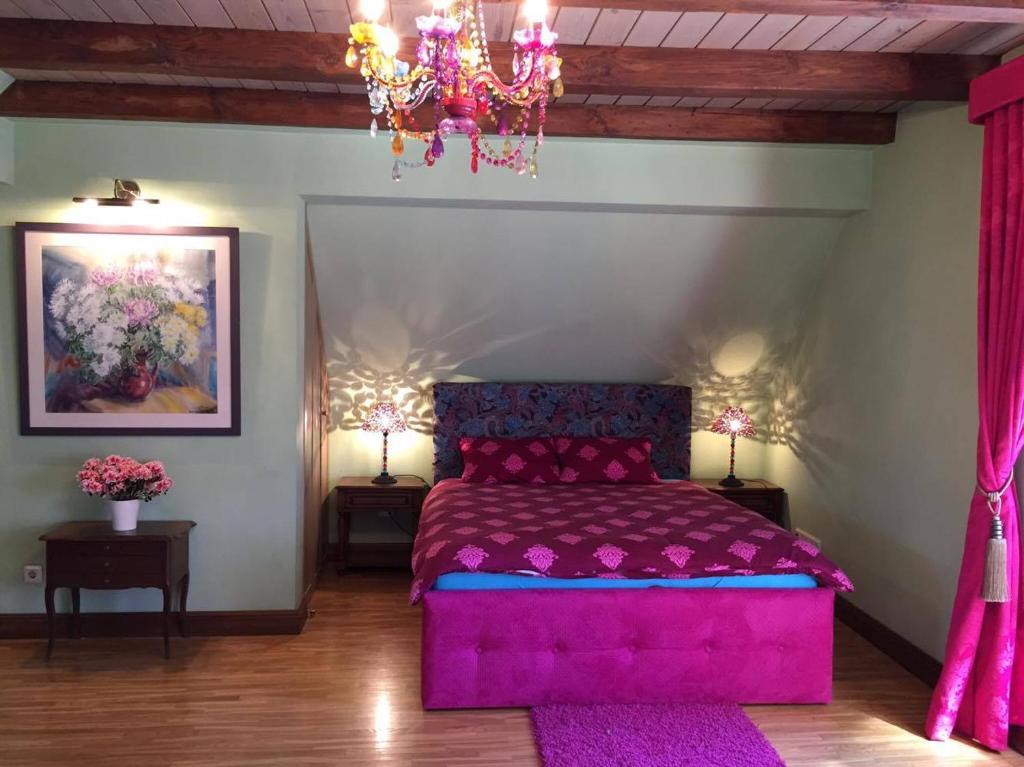a bedroom with a pink bed and a chandelier at Peahen Residence in Sigulda