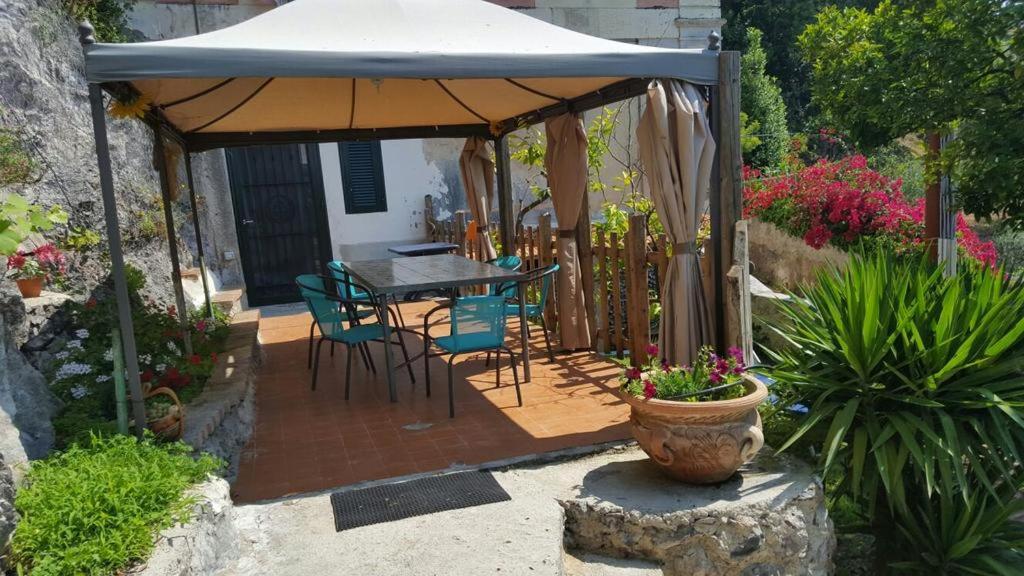 a patio with a table and chairs under an umbrella at Garden Bijou with Sea View in Vietri sul Mare