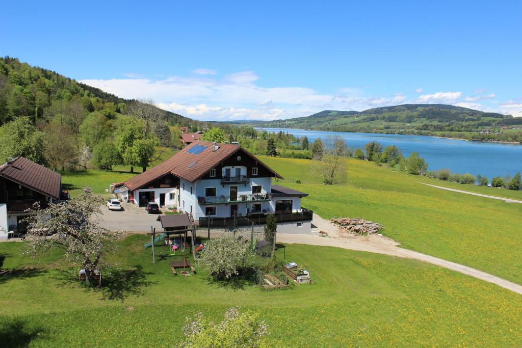 une grande maison sur une colline à côté d'un lac dans l'établissement Bauernhof Schink, à Zell am Moos