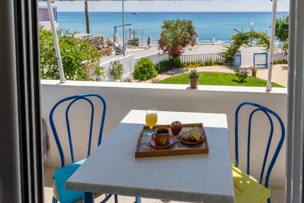 una mesa y sillas con un plato de comida en el balcón en Antonios Apartments Stegna, en Archangelos