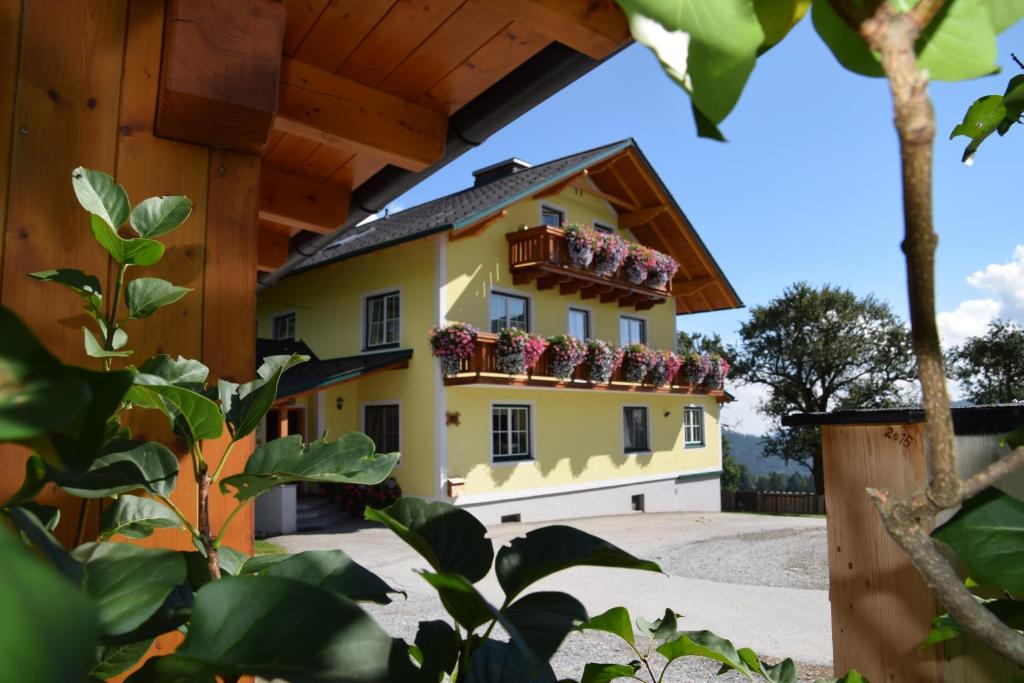 una casa amarilla con flores en el balcón en Huberhof im Almenland, en Sankt Kathrein am Offenegg