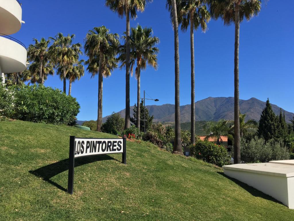 un cartel en el césped con palmeras en Estepona Golf - Los Pintores en Estepona