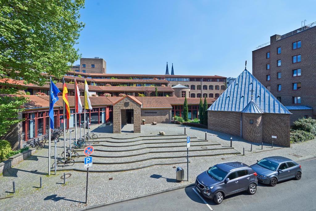 dos coches estacionados frente a un edificio con banderas en Maternushaus, en Colonia