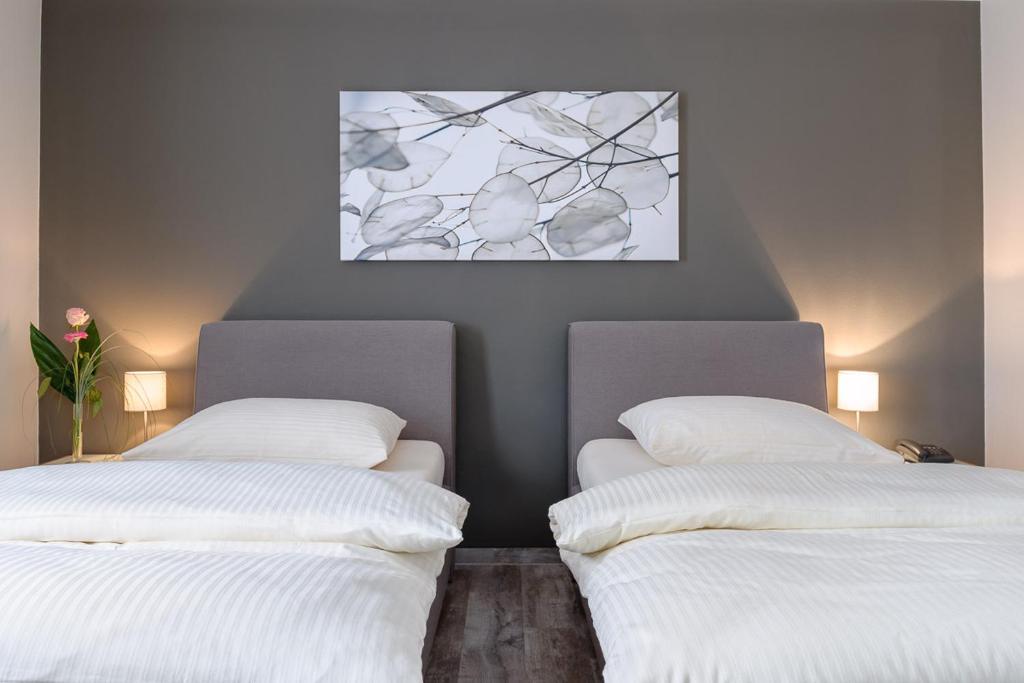 duas camas com lençóis brancos num quarto em sleepIN em Ingolstadt
