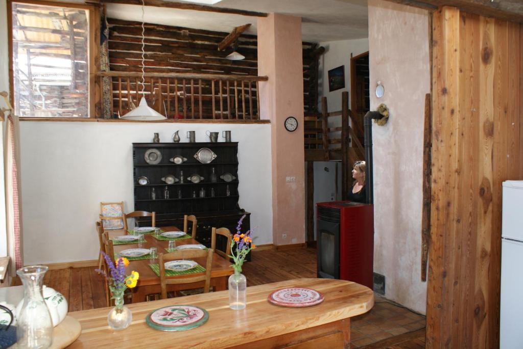 a kitchen and dining room with a table and a woman at le berger gourmand in Saint-Véran