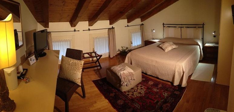 
a room with a bed, table, chairs and a lamp at La Dogana in Portogruaro
