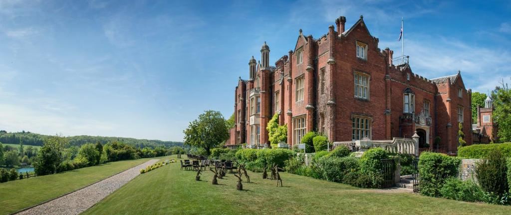 ein großes rotes Backsteingebäude mit Bänken davor in der Unterkunft De Vere Latimer Estate in Chesham