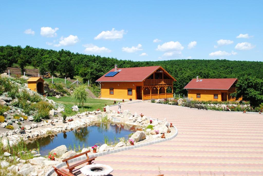 un edificio con un estanque en medio de un jardín en Rózsapark Vendégház, en Demjén