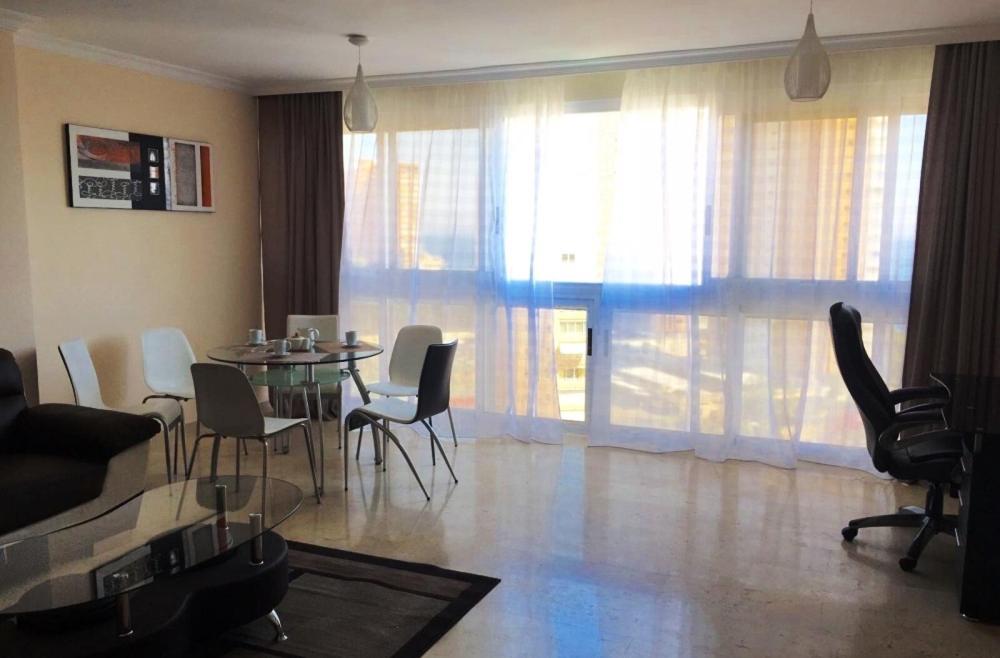 comedor con mesa de cristal y sillas en Apartament Costa Rica 2, en Benidorm