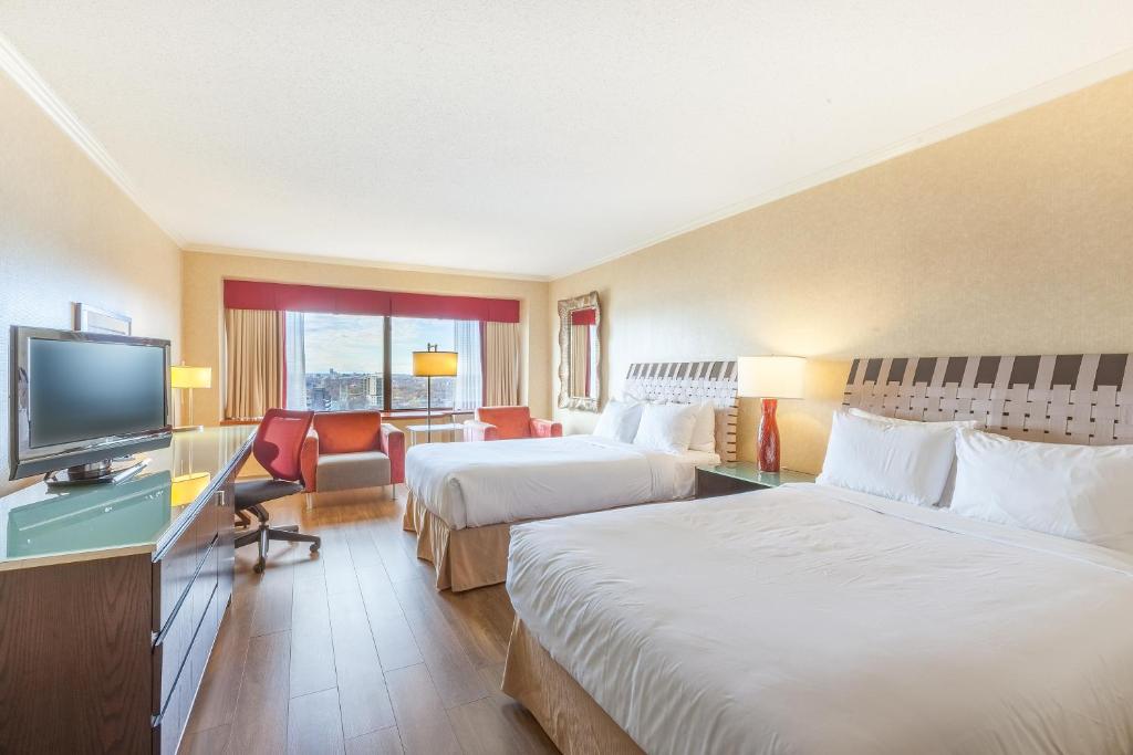 a hotel room with two beds and a flat screen tv at Hôtel Le Concorde Québec in Quebec City