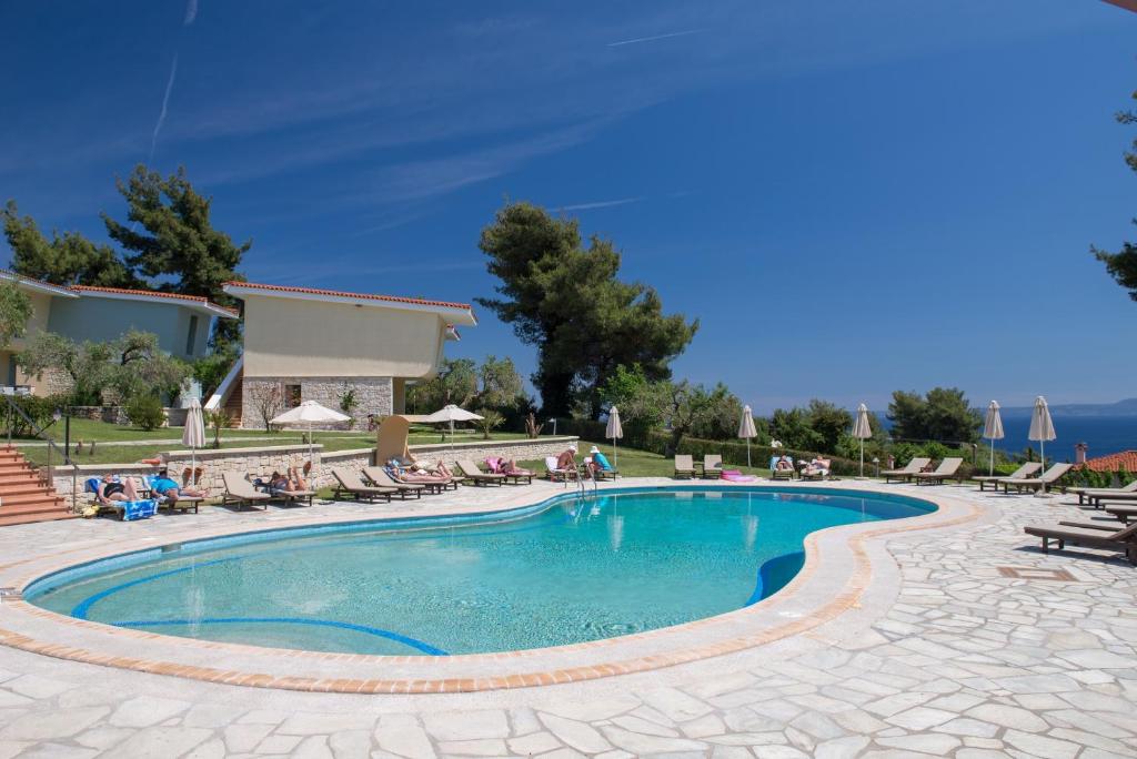 a swimming pool in a resort with people sitting around it at Alkion Hotel in Kriopigi