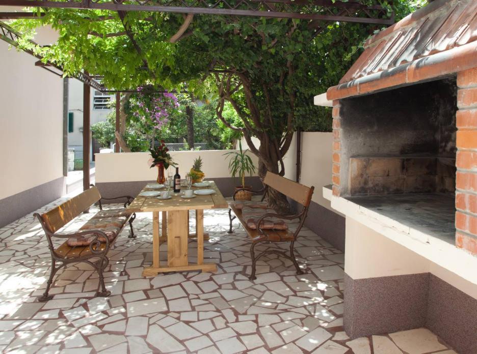 a patio with a table and chairs and a fireplace at Apartments Beautiful Sandy Beach in Split
