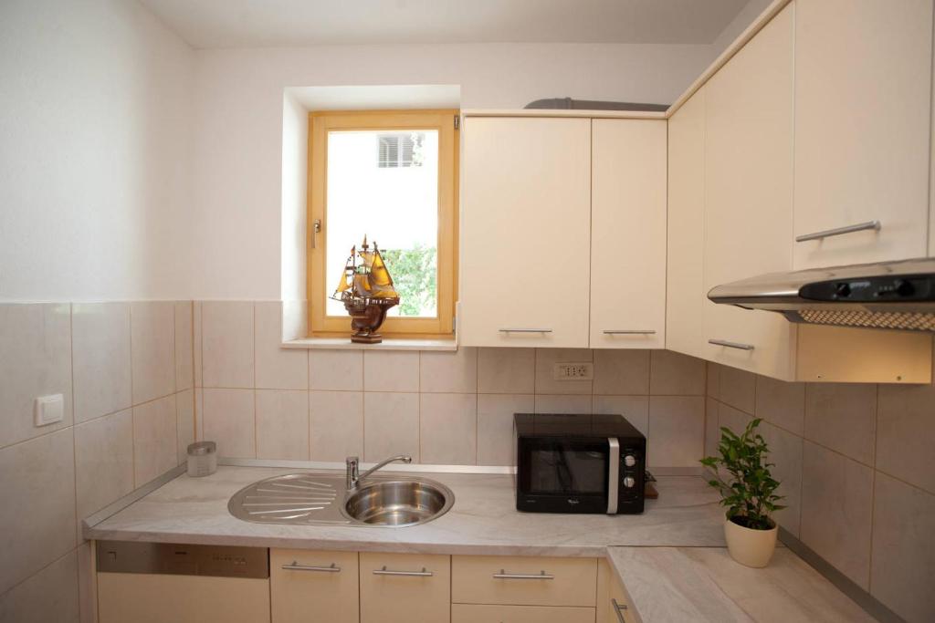 a kitchen with a sink and a microwave at Apartments Beautiful Sandy Beach in Split
