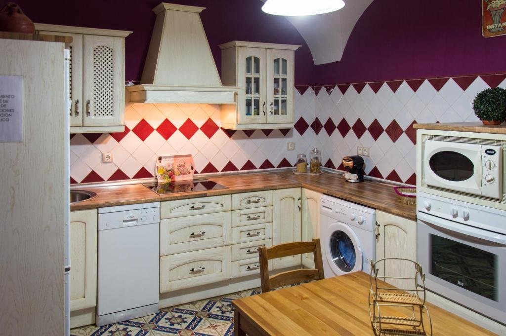 cocina con armarios blancos y paredes moradas en Casa Rural El Fuentarro, en Botija