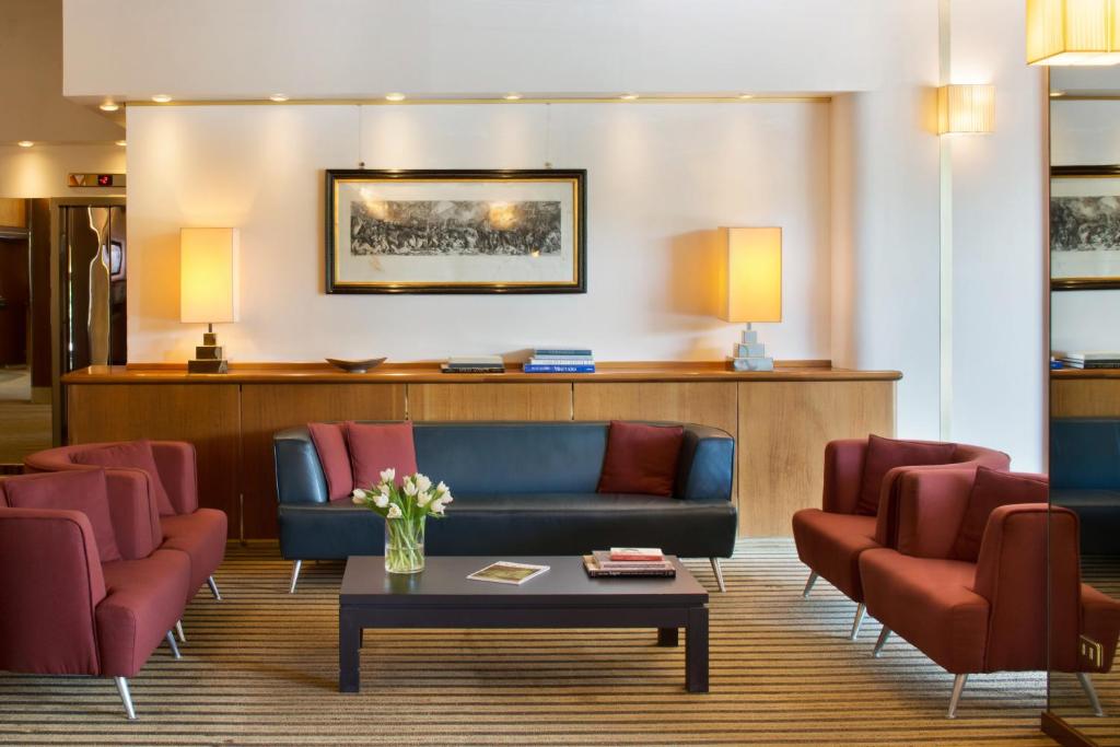 une salle d'attente avec un canapé bleu et des fauteuils rouges dans l'établissement Starhotels Cristallo Palace, à Bergame