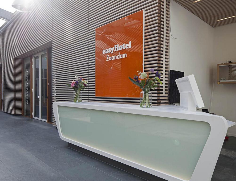 a reception desk in an office with flowers on it at easyHotel Amsterdam Zaandam in Zaandam