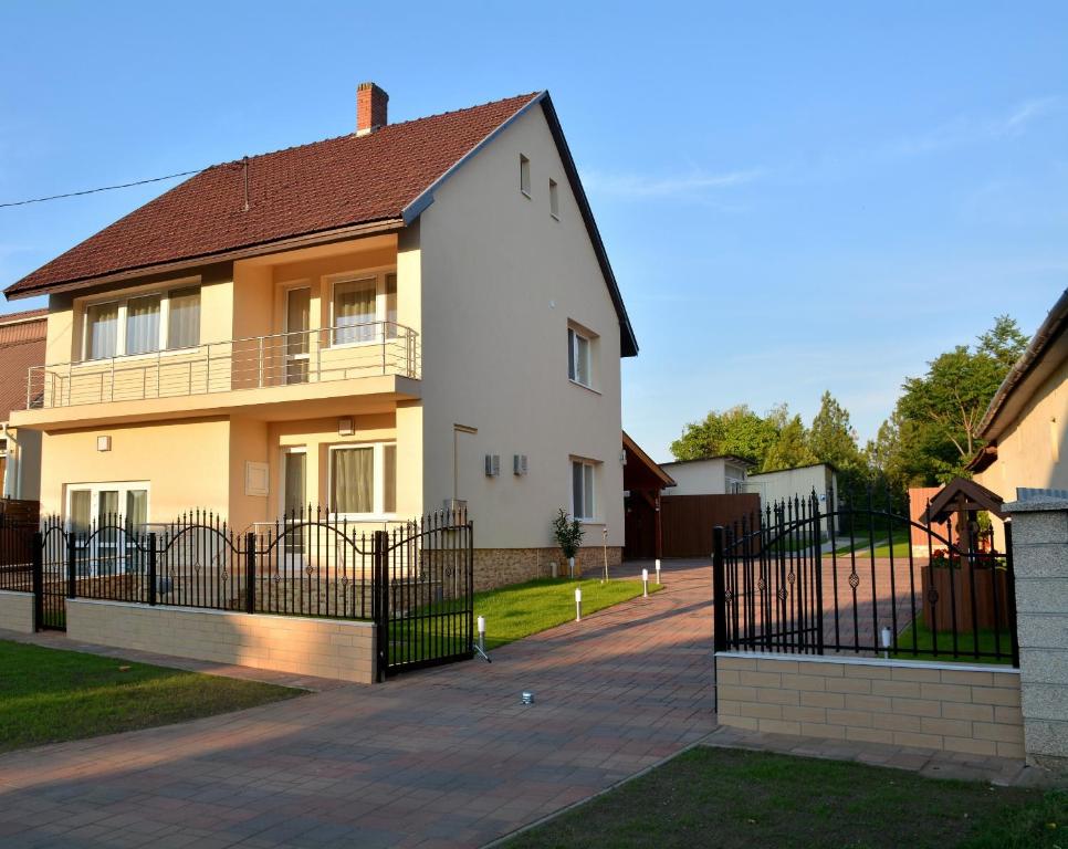 une maison blanche avec une clôture noire dans l'établissement Molnár Vendégház, à Újfehértó