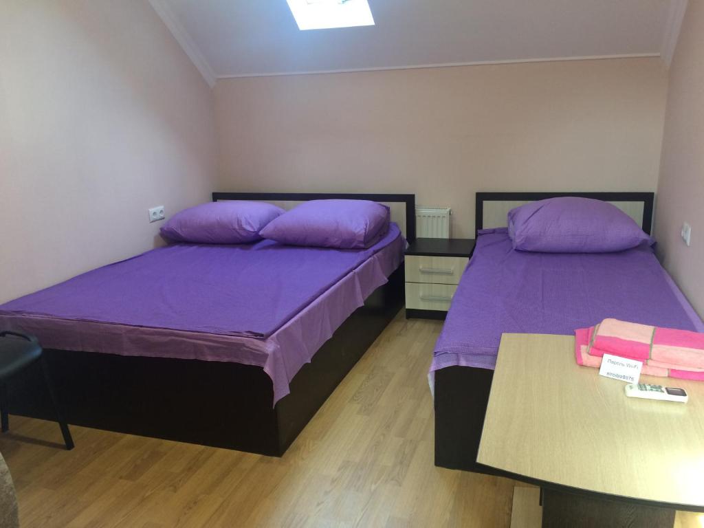 クシュチェフスカヤにあるGuesthouse na Kuybyshevaの紫色の枕とテーブルが備わる客室のベッド2台