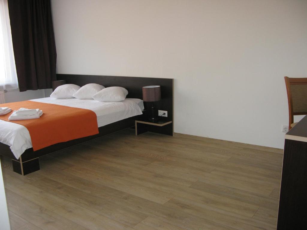 um quarto de hotel com uma cama com um cobertor laranja em Hotel Dobele em Dobele