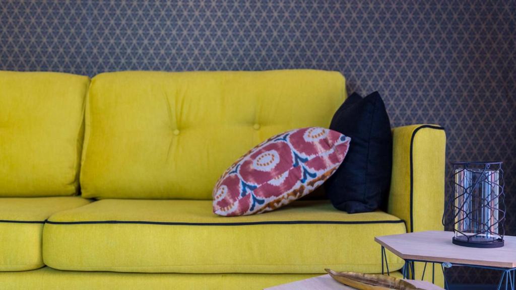 Un sofá amarillo con dos almohadas. en Groc Rooms, en La Seu d'Urgell