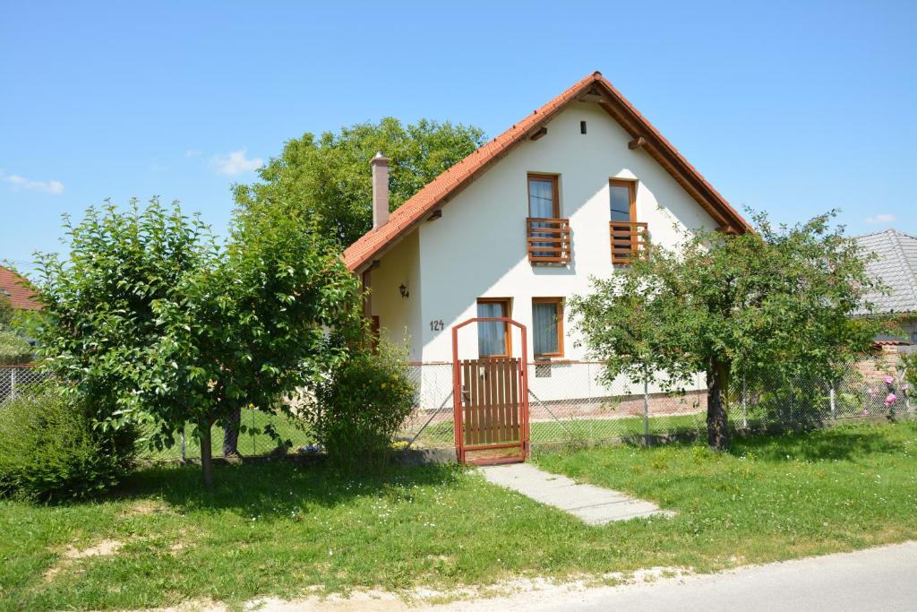 a white house with a red gate and two trees at Ágnes Apartman in Kaposvár