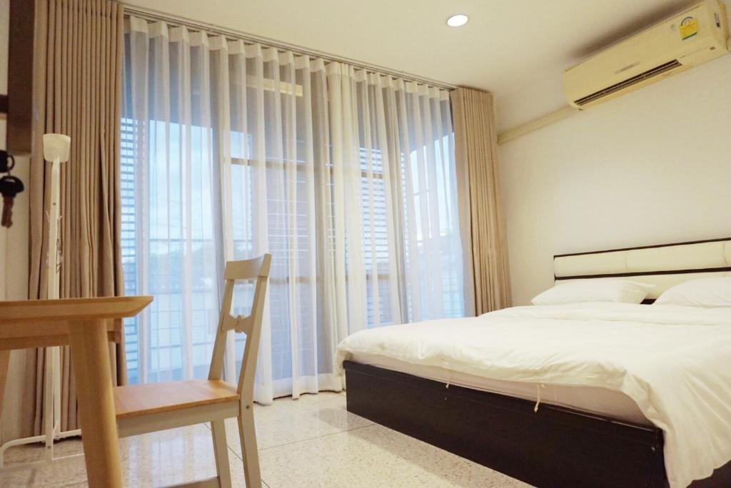 a bedroom with a bed and a desk and a window at Boon Street Hostel in Bangkok