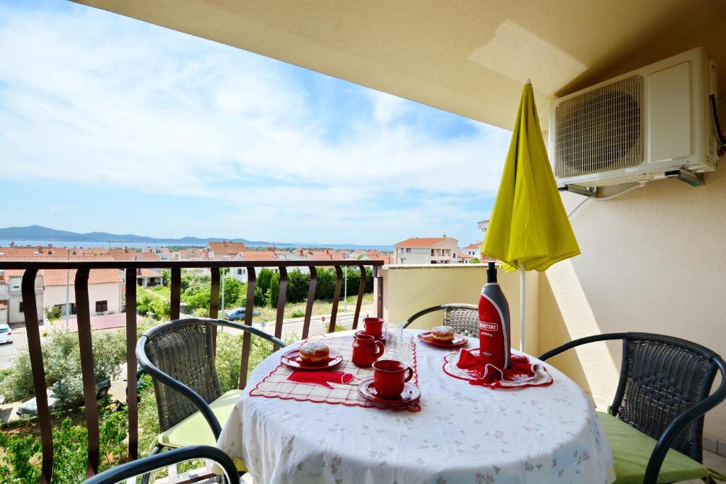 uma mesa com comida e um guarda-chuva amarelo numa varanda em Apartments Silvana sunset view em Zadar