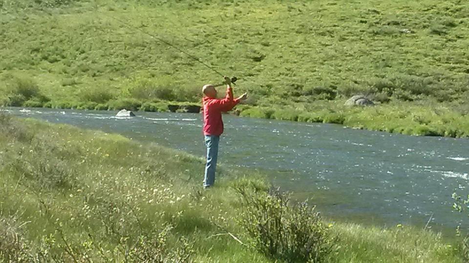 Un uomo è in piedi in un fiume con un aquilone di Narrow Gauge Railroad Inn ad Antonito