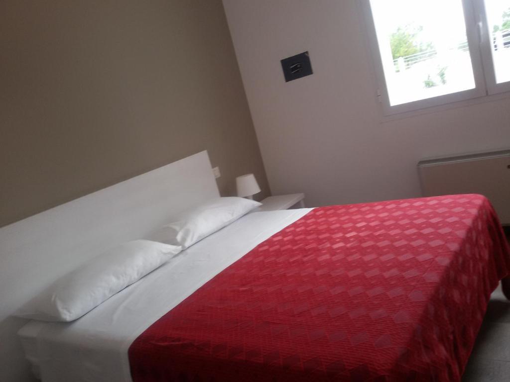 a bedroom with a red and white bed with a window at Blu Salentino in Porto Cesareo