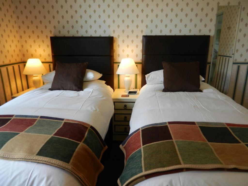 dos camas sentadas una al lado de la otra en un dormitorio en Overcombe House en Yelverton