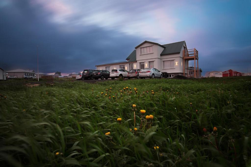 a house with cars parked in a field with flowers at Guesthouse Grund in Grindavík