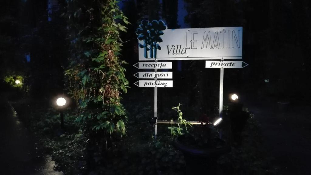 un cartello stradale con diversi cartelli di notte di Villa Le Matin a Konstancin-Jeziorna