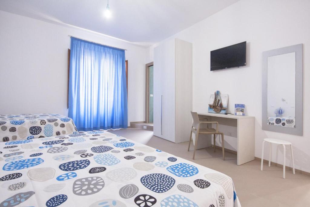 a white and blue bedroom with a bed and a desk at Le Nereidi in Castellammare del Golfo
