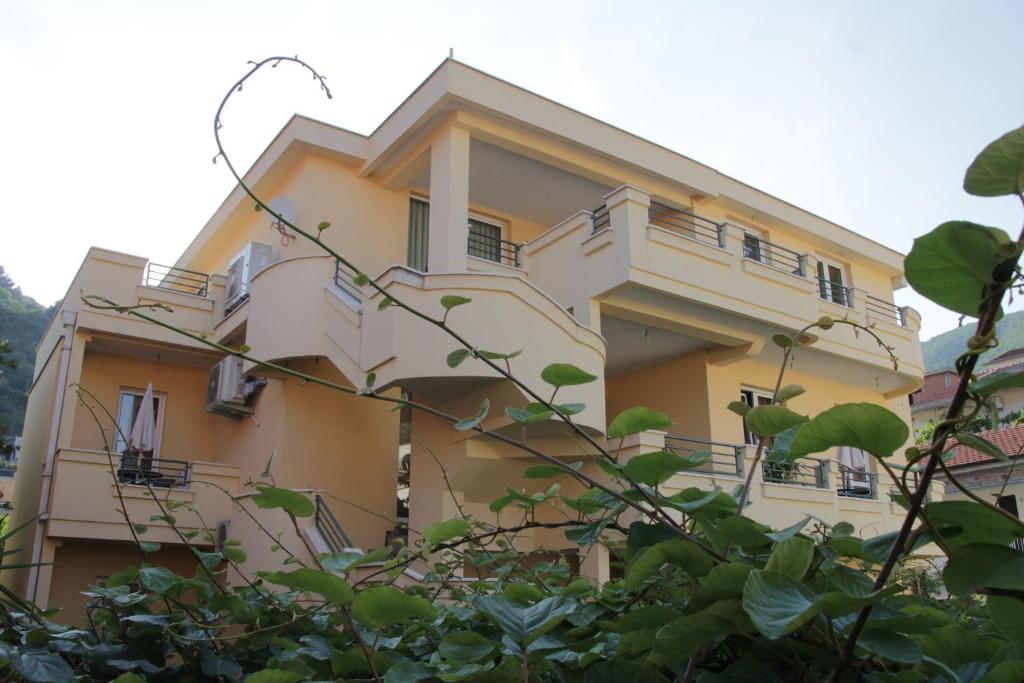 un edificio amarillo con balcones y árboles en Lilian Apartments en Budva