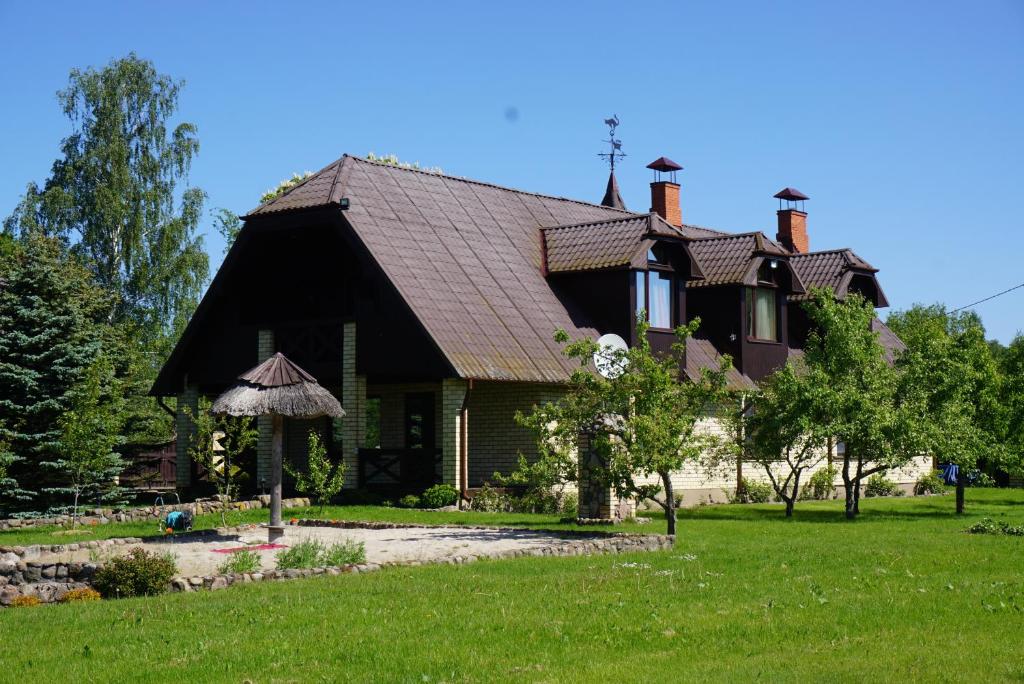 una casa con techo de gambrel en un césped verde en Hunting House Ezerkrasti en Lapmežciems