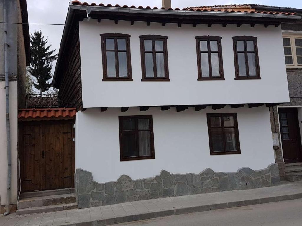 a white house with black windows and a fence at Guest House Strumena in Elena