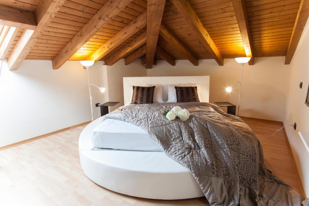 a large white bed in a room with wooden ceilings at AcquaTerraFuoco - City apartments in Como