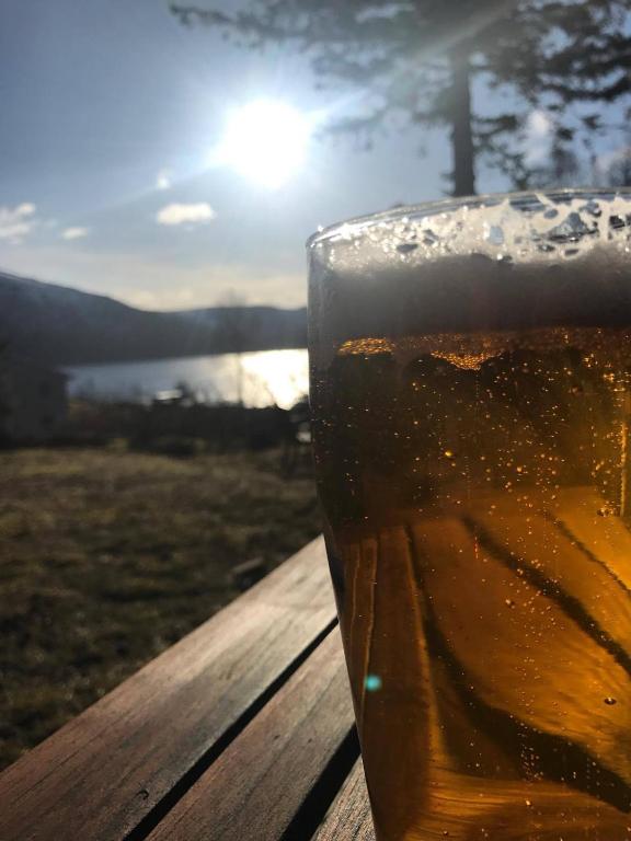 a glass of beer sitting on a table with the sunset at Stetind Hotel in Kjøpsvik