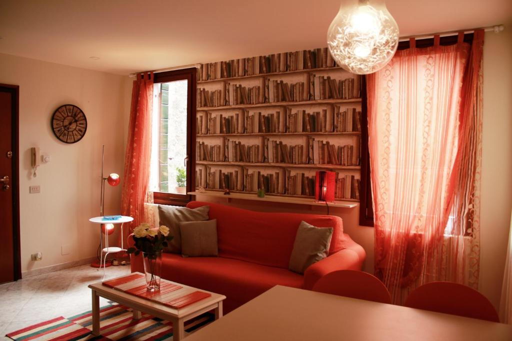 a living room with a red couch and bookshelves at Bacanal Apartment in Venice