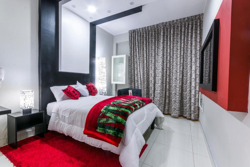 a bedroom with a large bed with a red blanket at Hotel El Rubi in Huaraz