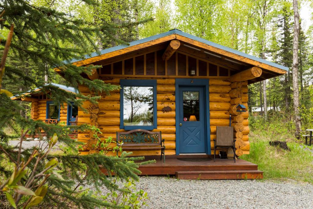 Cabaña de madera con puerta azul y banco en Hatcher Pass Cabins, en Palmer
