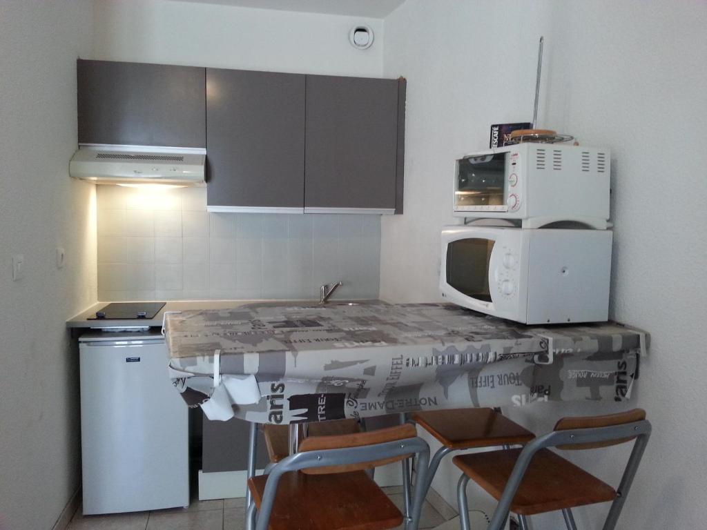 - une cuisine avec une table, des chaises et un four micro-ondes dans l'établissement Studio Toulon les Halles, à Toulon