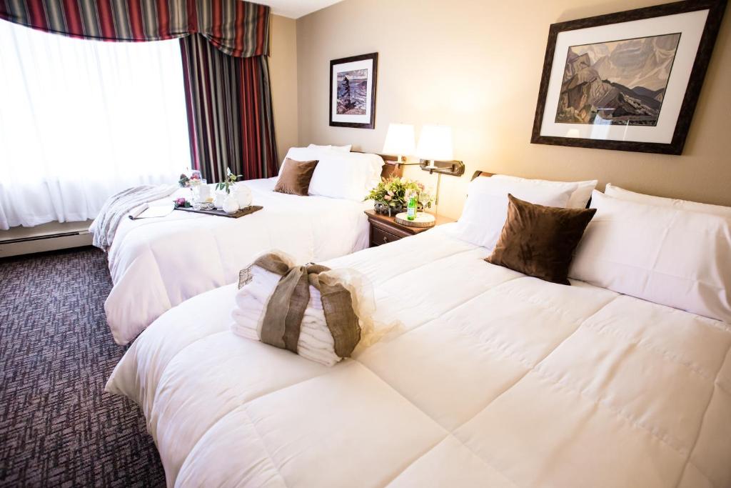 two beds in a hotel room with white pillows at Ramada by Wyndham Juneau in Juneau